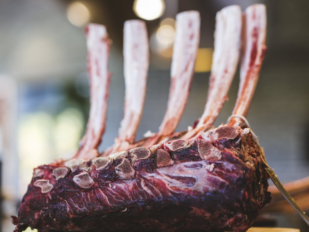 Close-up view of a raw rack of lamb ribs ready for cooking in a gourmet restaurant.