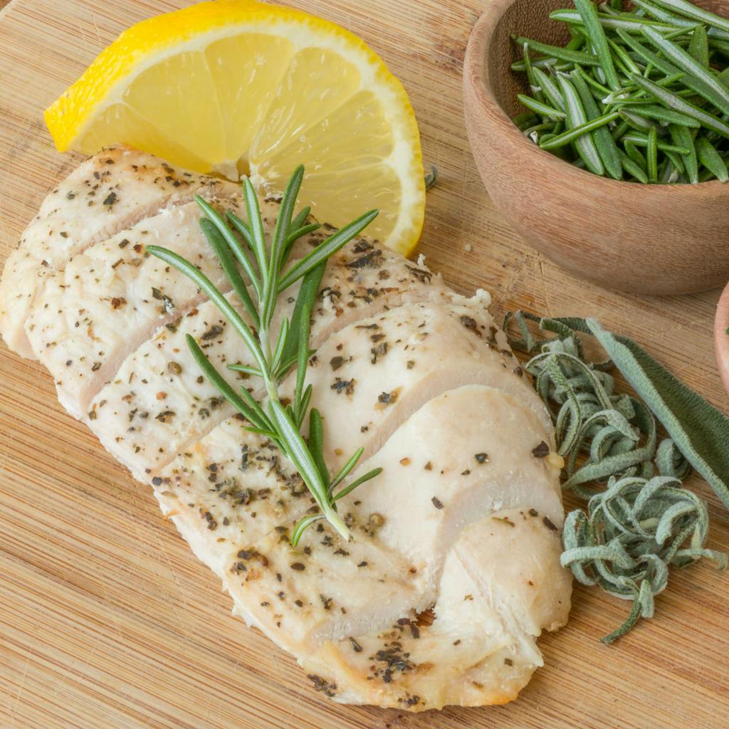 Delicious herb-crusted chicken breast garnished with rosemary and lemon slice.